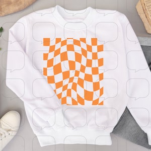 May include: White sweatshirt with a large orange and white checkered pattern graphic on the front.