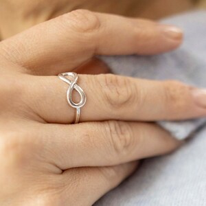 May include: A silver infinity ring on a finger.
