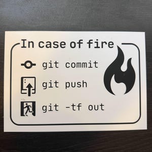 May include: White rectangular sign with black text and graphics. The text reads "In case of fire" followed by "git commit", "git push", and "git -tf out". A black flame graphic is on the right side.