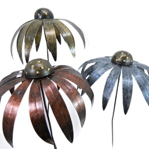 May include: Three metal garden stakes shaped like flowers with gold accents. The flowers are in shades of brown, copper, and grey.