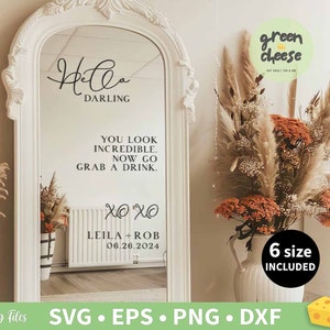 Puede incluir: Un espejo blanco y ornamentado con las palabras "Hello Darling" y un mensaje de boda. El espejo está decorado con flores secas y hierba de la pampa. El texto incluye "You look incredible. Now go grab a drink." y los nombres "Leila - Rob 06.26.2024".