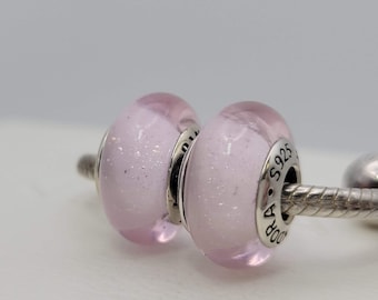 May include: Two pink glass beads with silver accents and the text "Pandora A.S 925" on one bead.