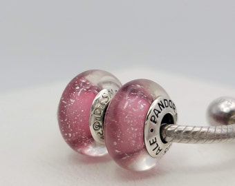 May include: Two pink glass beads with silver accents and the word "PANDORA" engraved on one bead. The beads are on a silver chain.