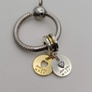 May include: A silver charm bracelet with a gold and silver charm that says "Love you most" and a silver charm that says "Love you more".