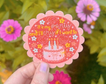 Peut inclure: Un autocollant rond à bord festonné avec le texte "It's my party and I'll cry if I want to." Il présente un gâteau rose avec des bougies, des cœurs et des motifs floraux. Des fleurs roses et des feuilles vertes en arrière-plan.