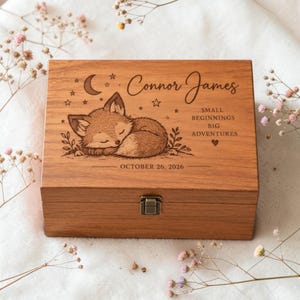 May include: A rectangular wooden keepsake box with a metal latch, featuring a laser-engraved sleeping fox, a crescent moon, stars, and the text "Connor James", "SMALL BEGINNINGS BIG ADVENTURES", and the date "OCTOBER 26, 2026" on the lid.