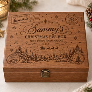 Puede incluir: Una caja de madera rectangular con un cierre de metal, grabada con el texto Sammy's CHRISTMAS EVE BOX, Special Delivery from the North Pole, North Pole Post, Holiday Express y Santa Approved, con una escena de pueblo invernal.