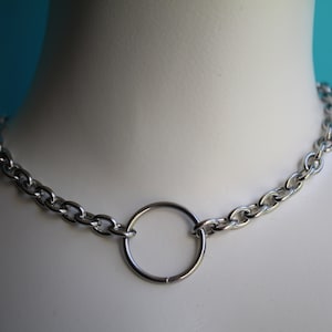 Könnte beinhalten: Eine silberne Kettenkette mit einem großen silbernen Ring in der Mitte.