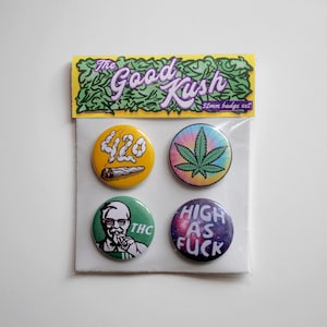May include: Set of four 32mm round pinback buttons with various designs related to cannabis culture. The buttons feature a green leaf, a cartoon of a person smoking, a galaxy background with the text "HIGH AS FUCK", and a white marijuana leaf with the number "420" in smoke.