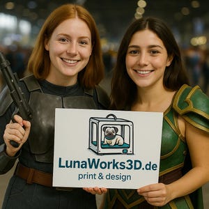 Może przedstawiać: Dwie uśmiechnięte osoby trzymają znak z napisem "LunaWorks3D.de print & design". Znak przedstawia kreskówkowego mopsa w drukarce 3D. Jedna osoba ma na sobie zbroję i trzyma blaster. Druga ma na sobie zielono-złoty kostium.