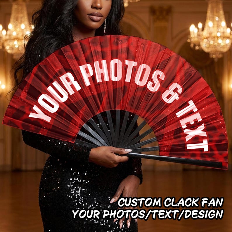 May include: A large, foldable hand fan featuring a deep red background with a subtle dark pattern. The fan displays the white text YOUR PHOTOS & TEXT in a bold, arched font across the fabric surface, supported by black ribs and a handle.
