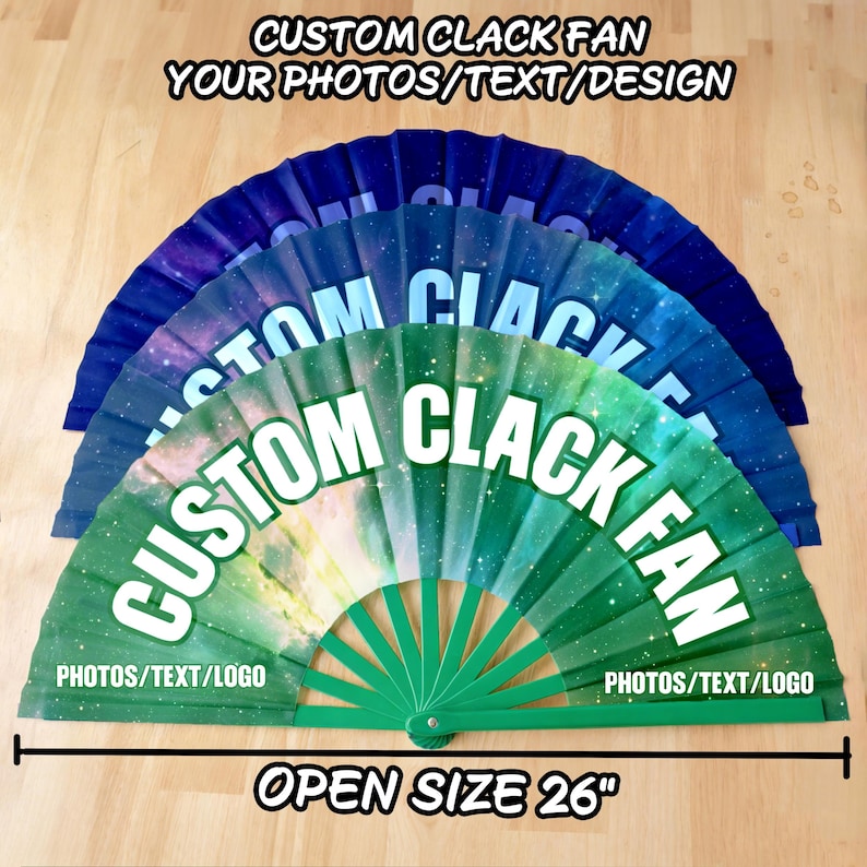 May include: Three folding hand fans with a galaxy print in green, blue, and dark blue. Each fan features the white text CUSTOM CLACK FAN and the text PHOTOS/TEXT/LOGO. A black measuring line indicates an open size of 26 inches for the fans.
