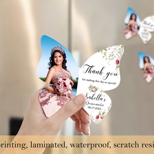 May include: Butterfly-shaped thank you cards with a floral design and a photo of a person in a quincea&ntilde;era dress. The text on the card reads "Thank you for making this day so special!" and "Isabella's Quinceanera 08.17.2025".