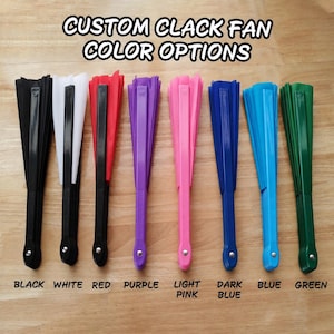 May include: Eight folding hand fans arranged in a row, each with a solid color handle and fabric. The text CUSTOM CLACK FAN COLOR OPTIONS appears at the top, with labels for black, white, red, purple, light pink, dark blue, blue, and green below.