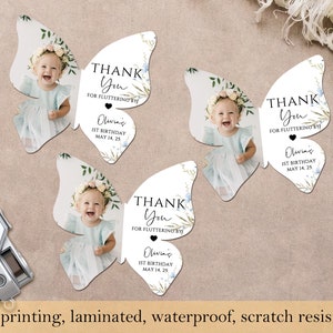 May include: Butterfly-shaped thank you cards with a baby's photo, floral details, and the text "Thank You for Fluttering By." The cards also include the text "Olivia's 1st Birthday May 14, 25." The cards are laminated and scratch resistant.