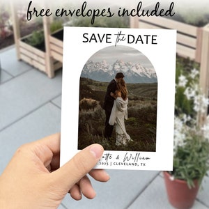 May include: Save the Date card featuring a photograph of a couple in front of a mountain range. The card text reads "Save the Date" and includes the couple's names, date, and location.