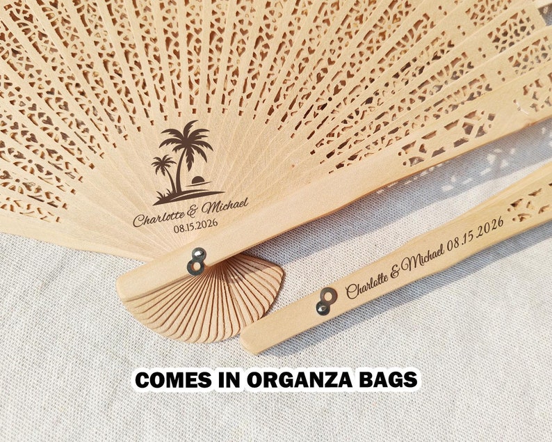 May include: A wooden hand fan with a palm tree design and the text "Charlotte & Michael 08.15.2026".
