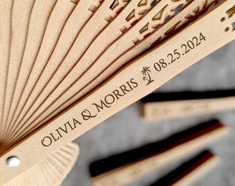 Könnte beinhalten: Ein Fächer aus Holz mit einem geschnitzten Design und dem Text "Olivia & Morris 08.25.2024" und einem Palmensymbol.