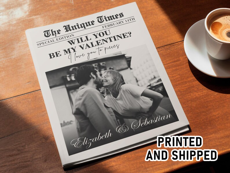 May include: A newspaper-style print with a black and white photo of a couple kissing. The headline reads "WILL YOU BE MY VALENTINE?" with the names "Elizabeth & Sebastian" below the photo. A cup of coffee sits nearby.