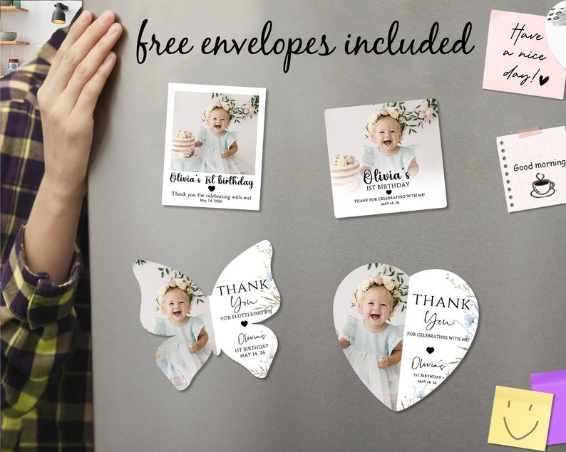May include: A selection of personalized birthday and thank you cards, including butterfly and heart-shaped designs. The cards feature a baby's photo, floral accents, and the text "Olivia's 1st Birthday" and "Thank You". The phrase "free envelopes included" is also visible.