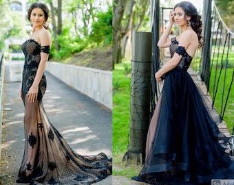 Könnte beinhalten: Eine Frau in einem schwarzen, schulterfreien Kleid mit Spitzendetails und einem Tüllrock. Das Kleid hat ein figurbetontes Oberteil und einen fließenden Rock. Die Frau steht in einer Gartenlandschaft.