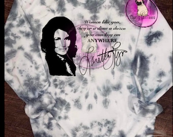 May include: A white sweatshirt with a black and white tie-dye pattern. The sweatshirt features a black and white image of a woman with the text "Women like you, they're a dime a dozen, you can buy 'em ANYWHERE" and a signature.