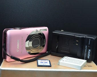 Rosa Cámara digital compacta Canon PowerShot SD1300 IS Digital Elph de 12MP con batería nueva, cargador original y tarjeta SD de 1GB. Probado/funcionando.