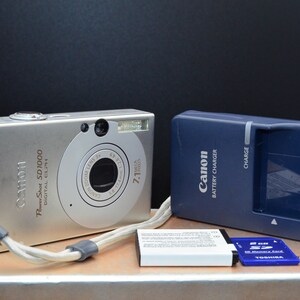 Canon PowerShot SD1000 7MP CCD digital camera. Includes the original box, cables, charger, cables, 2GB SD card and new battery. Working