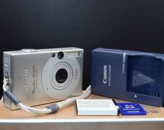 Canon PowerShot SD1000 7MP CCD digital camera. Includes the original box, cables, charger, cables, 2GB SD card and new battery. Working