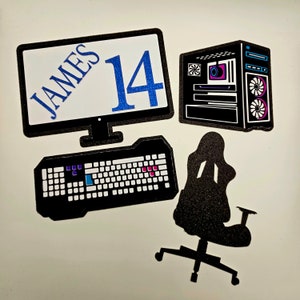 May include: A black computer monitor with the text "JAMES 14" on the screen, a black keyboard, a black computer tower, and a black gaming chair.