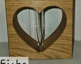 Op de afbeelding: Een houten blok met een hartvormige uitsparing, met een heldere glazen buis. Het blok is gemaakt van lichtbruin hout, met het woord "Eiche". Het eenvoudige en elegante ontwerp is geschikt voor een enkele bloem.