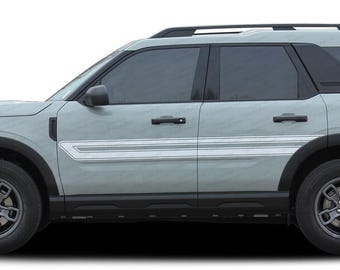May include: A light gray Ford Bronco Sport SUV with black trim and silver accents. The vehicle is shown in profile view with the driver's side facing the camera.