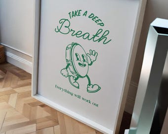 May include: White framed print with green text that reads "Take a deep Breath" and a cartoon illustration of a green drum with eyes and arms. The text "Everything will work out" is below the illustration.