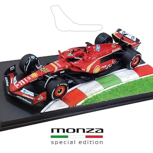 Può includere: Modello di auto da corsa di Formula 1 rossa su base nera, con una sezione di pista. L'auto ha loghi degli sponsor e il numero 16. La base ha le parole "monza" e "special edition".