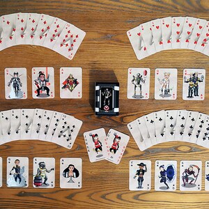 May include: A deck of playing cards with illustrated characters on the face cards. The cards are arranged in a fan shape, with the suits of hearts, diamonds, clubs, and spades visible. There are two Jokers in the center of the image.