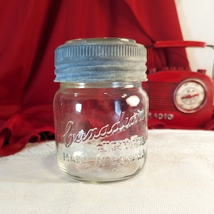 Peut inclure: Un pot en verre transparent avec un couvercle argenté. Le pot est étiqueté "Bernardin" et "Jewel" et indique "Fabriqué au Canada".