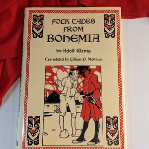Może przedstawiać: Książka zatytułowana "Folk Tales from Bohemia" autorstwa Adolfa Weniga, przetłumaczona przez Lillian P. Mokrejs. Okładka przedstawia czarno-białą ilustrację dwóch mężczyzn w strojach z epoki, jeden w czerwonym płaszczu, a drugi w białej koszuli i spodniach.