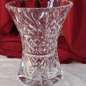 May include: A clear glass vase with a cut crystal design. The vase has a wide mouth and a narrow base.