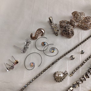 May include: Assortment of silver and rhinestone jewellery including earrings, a brooch, a necklace, and a hair clip.