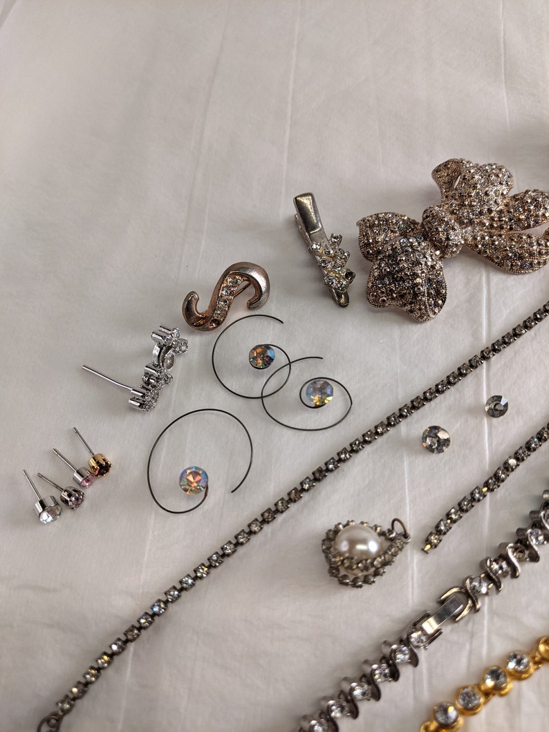May include: Assortment of silver and rhinestone jewellery including earrings, a brooch, a necklace, and a hair clip.