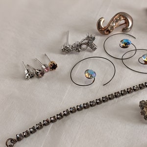 May include: Assortment of jewellery pieces including a silver and crystal earring, a silver and crystal pendant, a silver and crystal bracelet, and a silver and crystal ring.