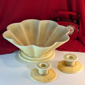 Puede incluir: Un conjunto de tres piezas de cerámica vintage de color amarillo pálido. El conjunto incluye un tazón grande con forma de concha con una base de pedestal y dos candelabros a juego.