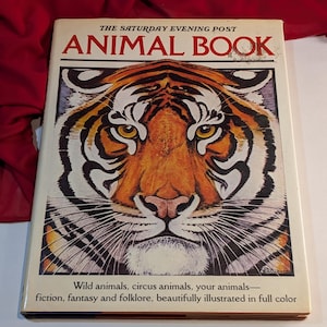 Könnte beinhalten: Der Einband eines Buches mit dem Titel "The Saturday Evening Post Animal Book". Der Einband zeigt eine Nahaufnahme eines Tigergesichts.