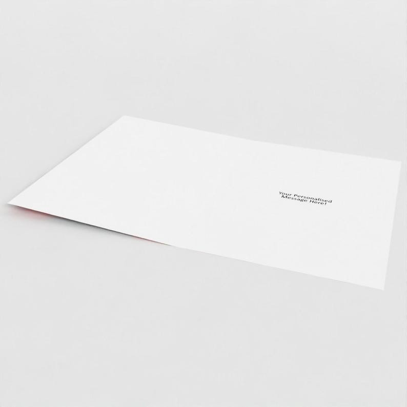 May include: A white greeting card with the text "Your Personalised Message Here!" printed in black. The card has a red edge and is slightly angled, suggesting it's open or partially folded.