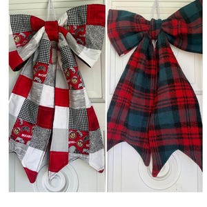 May include: Two decorative fabric bows. The left bow features a patchwork design with red, white, black, and gray squares, including Ohio State University logos. The right bow is made of a red, black, and dark green plaid fabric with pointed tails.