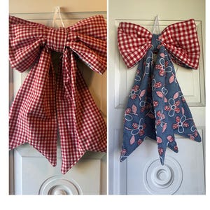 May include: Two fabric bows with hanging tails. The left bow features a red and white gingham check pattern. The right bow displays a red and white gingham check pattern on the top loops and a blue fabric with a red and white floral print on the tails.