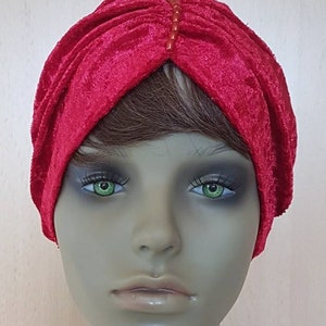 May include: A red velvet turban with a beaded embellishment on the top.