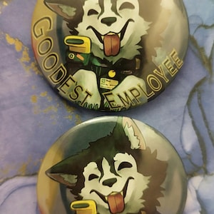 May include: Two round buttons with a cartoon husky dog illustration. The dog has a happy expression with its tongue out. The text "GOODEST EMPLOYEE" is printed around the dog.