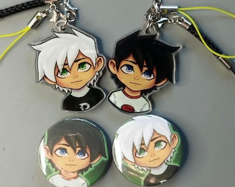 May include: Two clear acrylic charms and two round buttons featuring cartoon characters with white and black hair, green and blue eyes, and wearing t-shirts. The charms have black cords and silver clasps. The buttons have a green background.