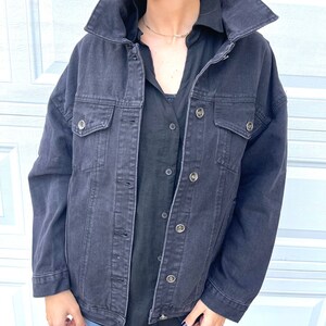 Peut inclure: Une veste en jean noire &agrave; la coupe d&eacute;contract&eacute;e et plusieurs poches. La veste se ferme par des boutons et poss&egrave;de un col classique.